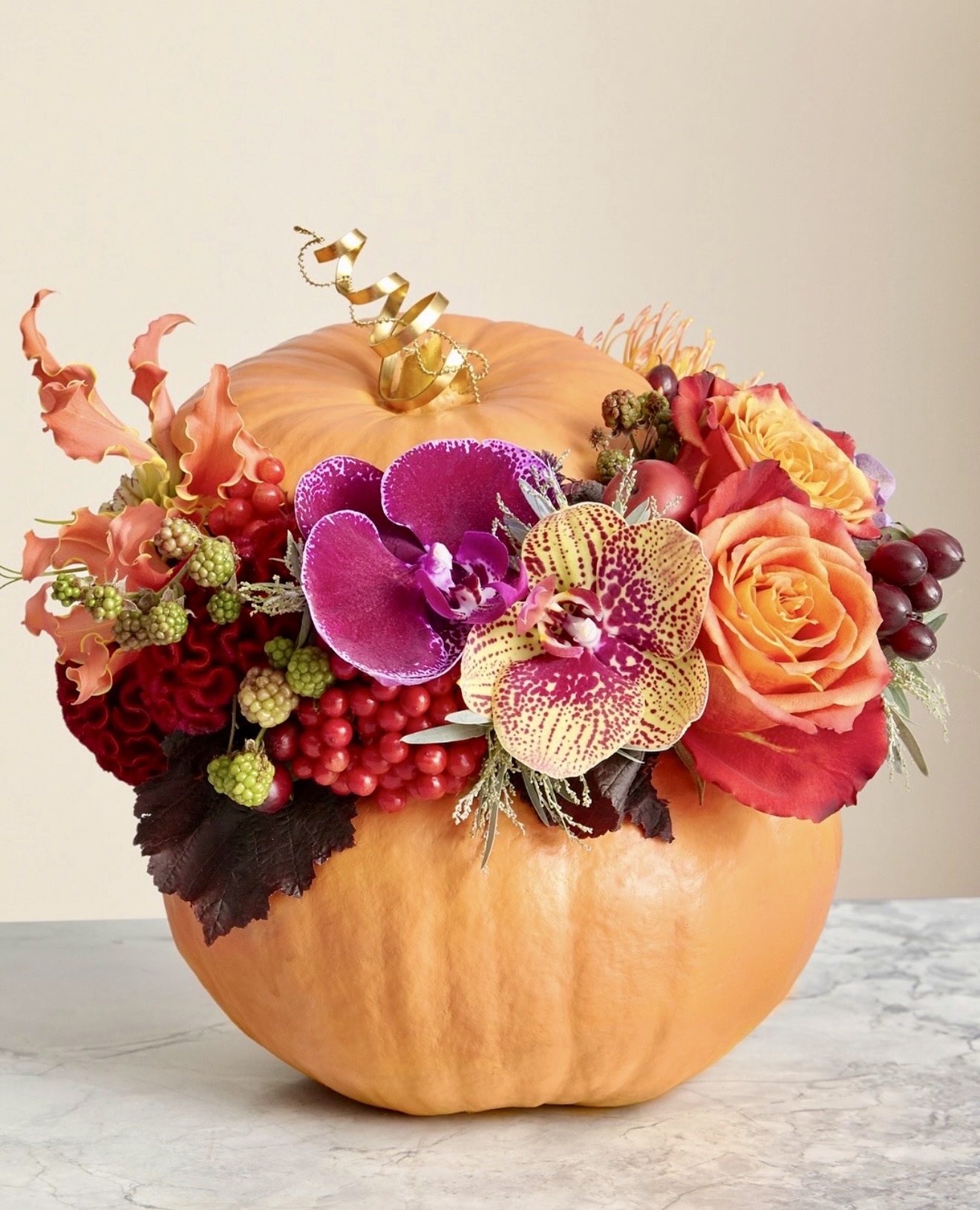 Pumpkin floral arrangement with orchids and roses